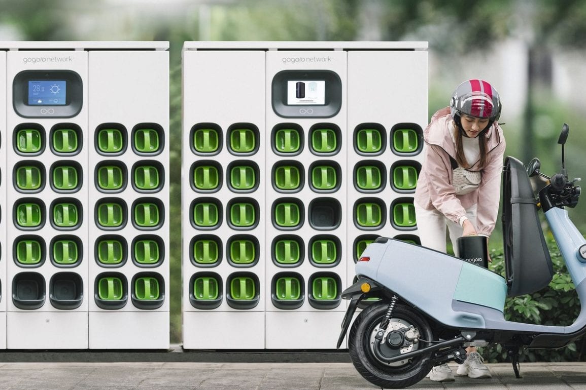 Girl swapping batteries out of an electric scooter at Gogoro battery-swapping platform