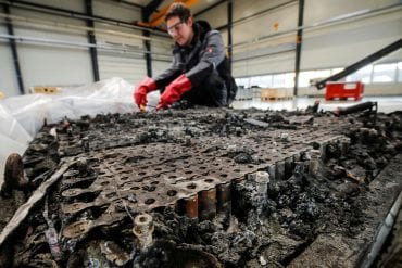 A technician checks the possible remaining voltage of a completely burned Lithium-ion car battery before its dismantling by the German recycling firm Accurec in Krefeld