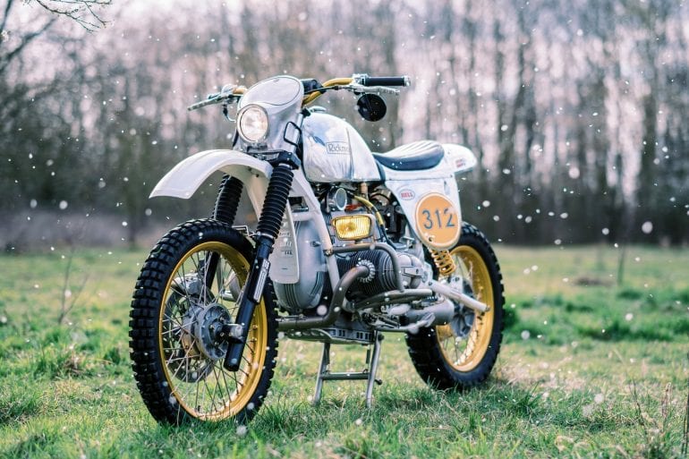 BMW Enduro custom motorcycle in a grassy field with flower petals falling