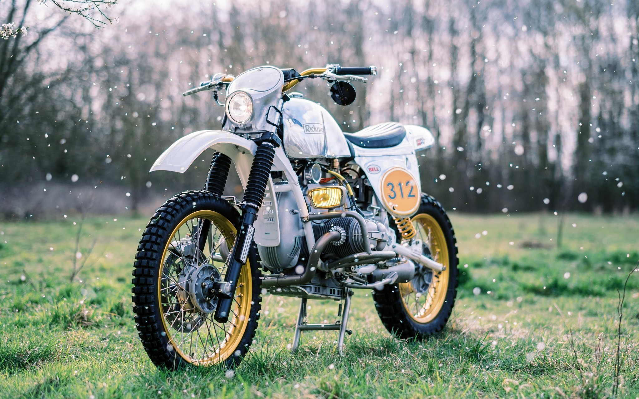 BMW Enduro custom motorcycle in a grassy field with flower petals falling
