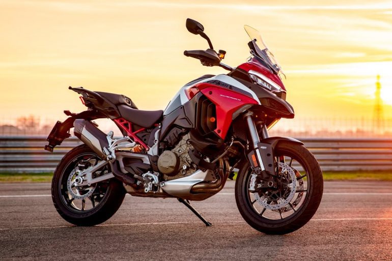 A static shot of the Ducatil Multistrada V4 on a track as the sun sets in the background with a golden hue
