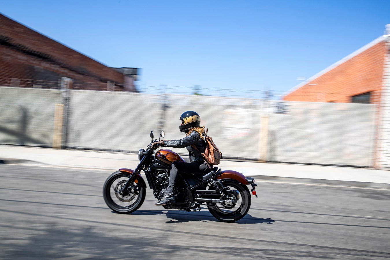 A lady riding down the street on a Honda Rebel